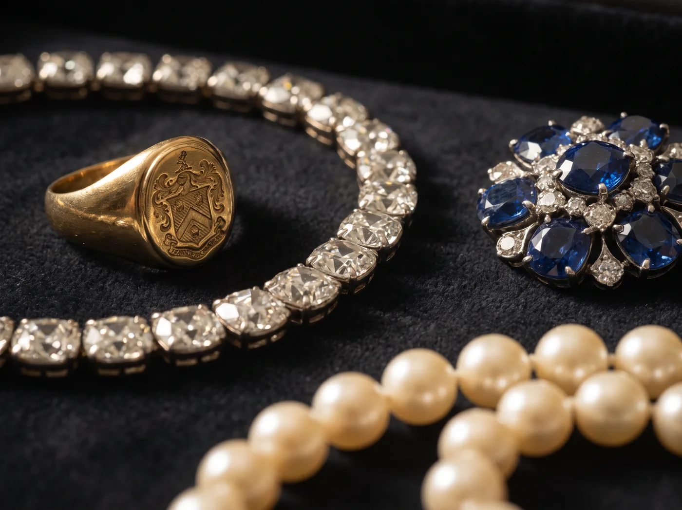 Diamantcollier, Goldring und Brosche auf dunklem Samt