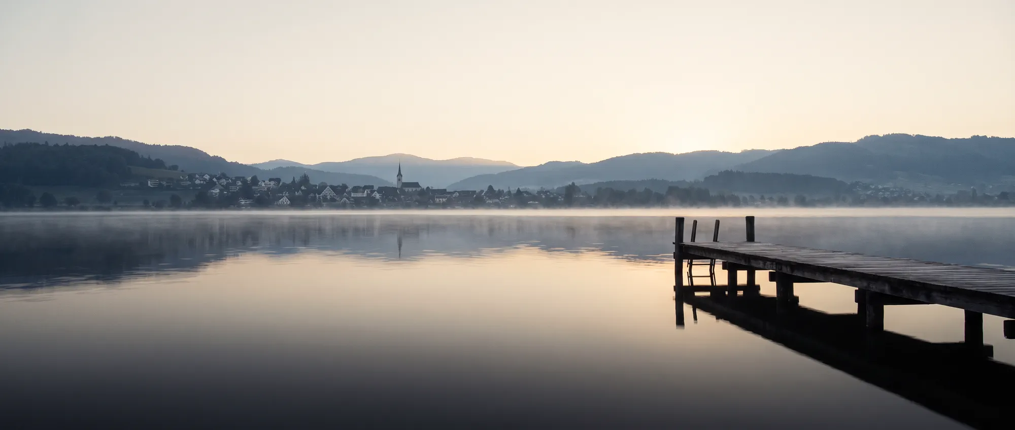 Zürichsee im Morgennebel mit Blick über das rechte Seeufer